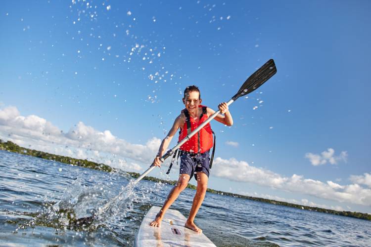 Boy splashing water while on a paddleboard