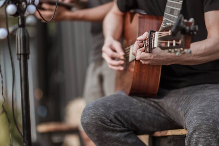 man on a stool holding a guitar