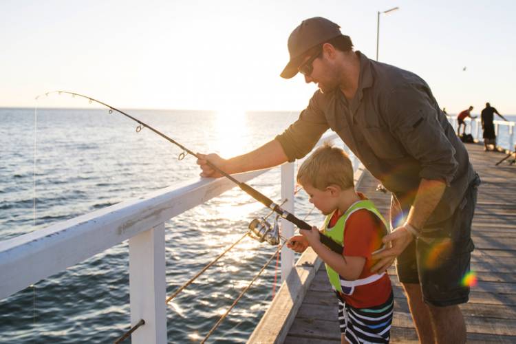 A father and son fish on a pier