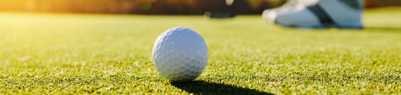 A man putts a ball into the hole